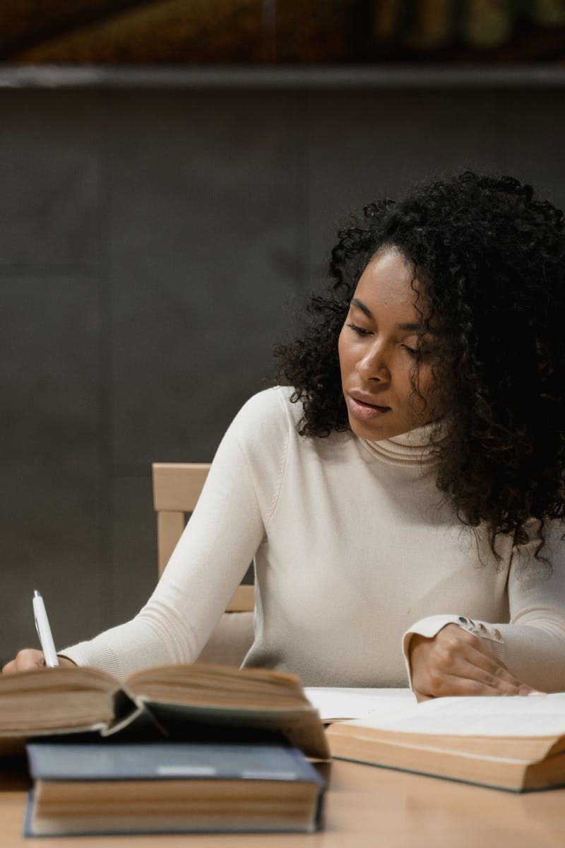 A focused woman writing and studying inside a modern library.